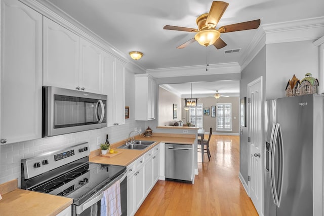 kitchen featuring a sink, crown molding, white cabinets, and stainless steel appliances