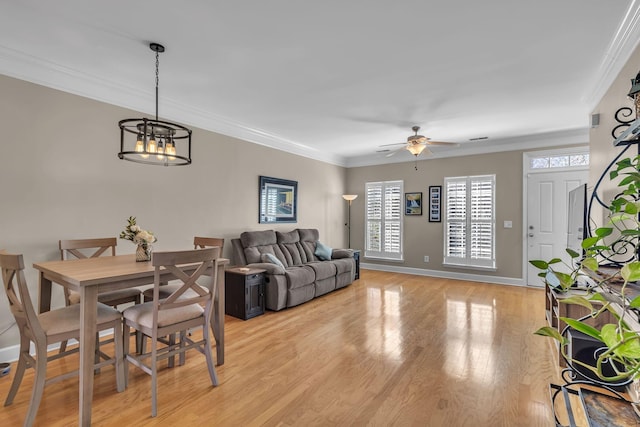 living area featuring light wood-style flooring, ceiling fan with notable chandelier, crown molding, and baseboards