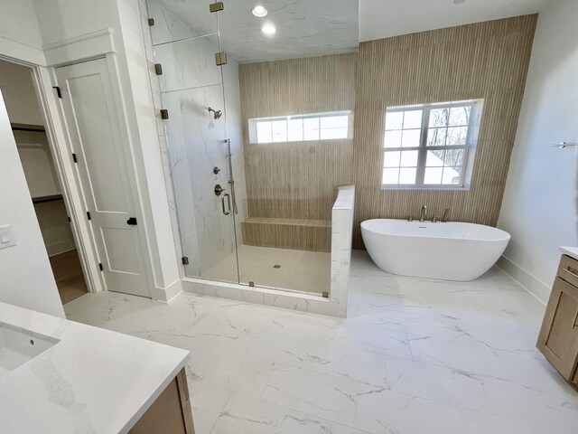 full bath with a soaking tub, marble finish floor, a stall shower, and vanity