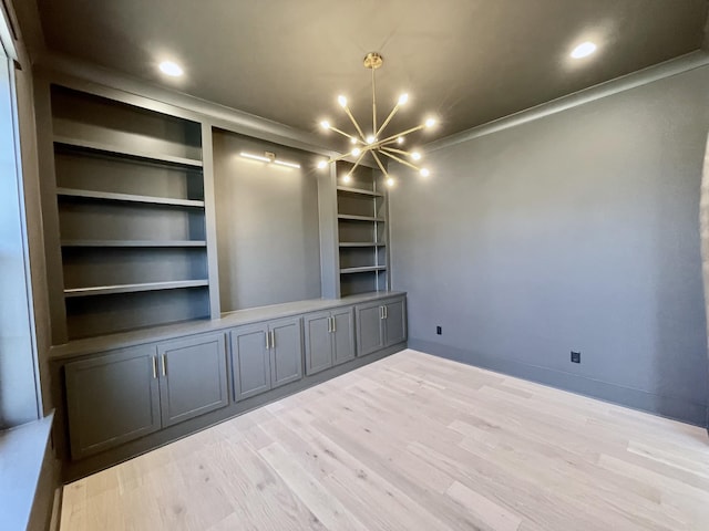 empty room featuring a chandelier, built in features, recessed lighting, and wood finished floors