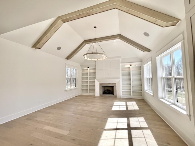 unfurnished living room featuring vaulted ceiling with beams, a large fireplace, baseboards, built in features, and light wood-type flooring