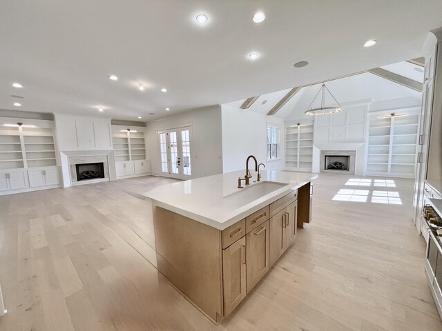 kitchen with light wood-style flooring, a fireplace, open floor plan, and french doors