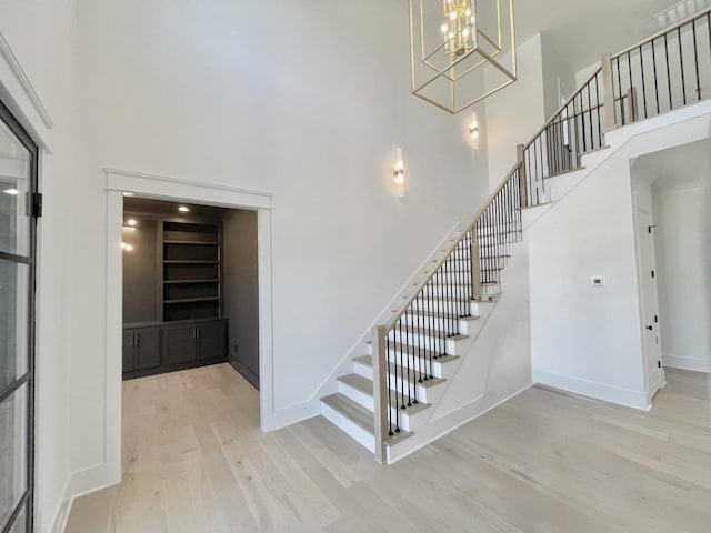 staircase with baseboards, wood finished floors, and a towering ceiling