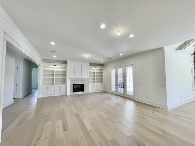 unfurnished living room featuring baseboards, light wood finished floors, a fireplace, recessed lighting, and french doors