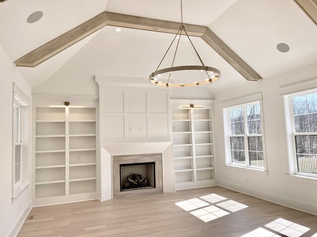 unfurnished living room with baseboards, built in features, light wood-type flooring, lofted ceiling with beams, and a fireplace