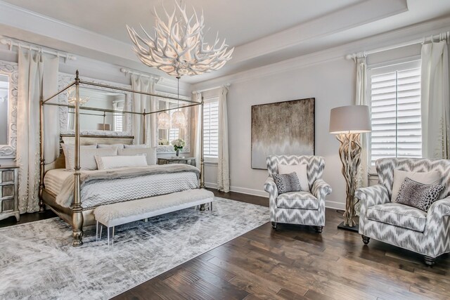 bedroom featuring crown molding, baseboards, wood finished floors, a notable chandelier, and a raised ceiling