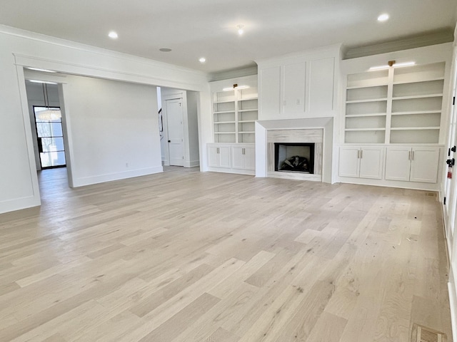 unfurnished living room with visible vents, light wood-style floors, a fireplace, crown molding, and baseboards