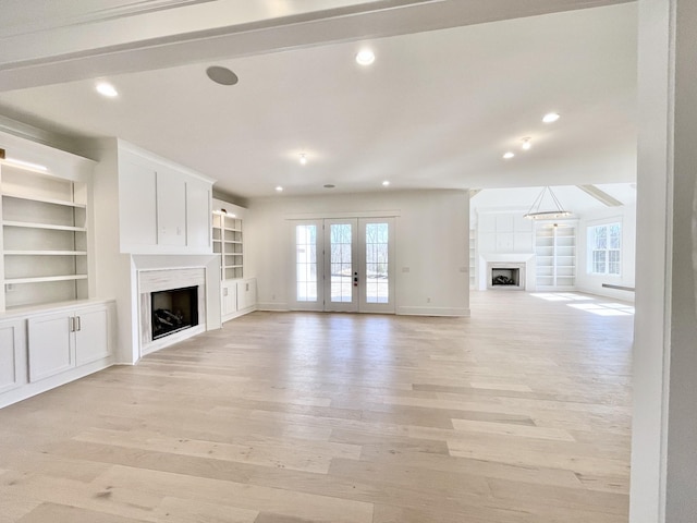 unfurnished living room with plenty of natural light, a fireplace, and light wood finished floors