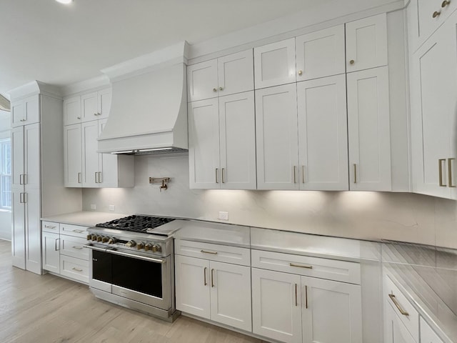 kitchen with double oven range, white cabinetry, custom exhaust hood, and light countertops