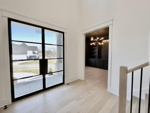 interior space with light wood finished floors, a notable chandelier, stairway, and baseboards