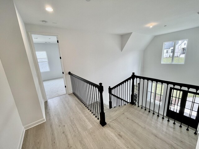 corridor featuring a wealth of natural light, baseboards, and wood finished floors