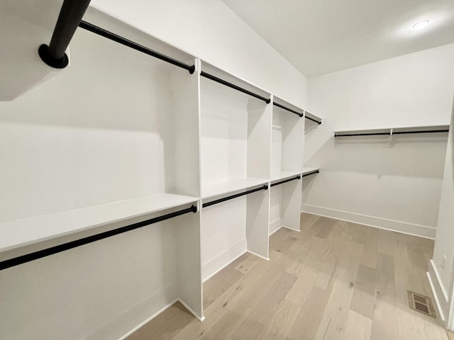 walk in closet featuring a barn door, visible vents, and light wood-type flooring