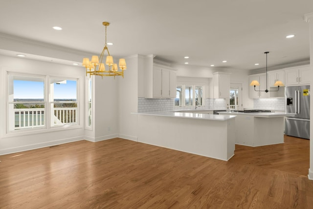 kitchen featuring backsplash, high end fridge, wood finished floors, and an inviting chandelier