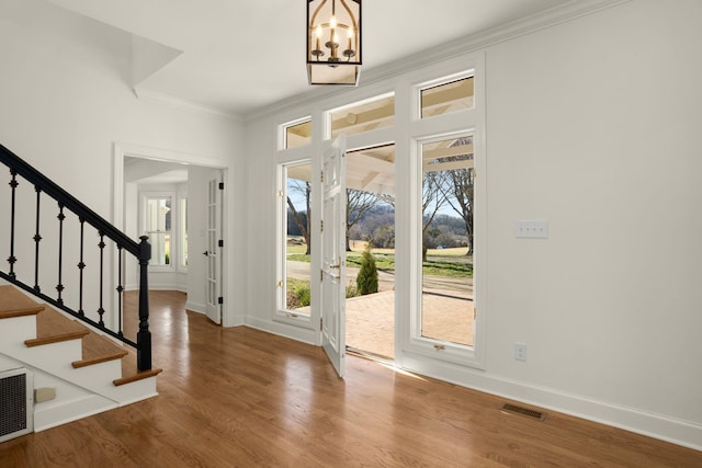 entryway featuring visible vents, baseboards, stairway, ornamental molding, and wood finished floors