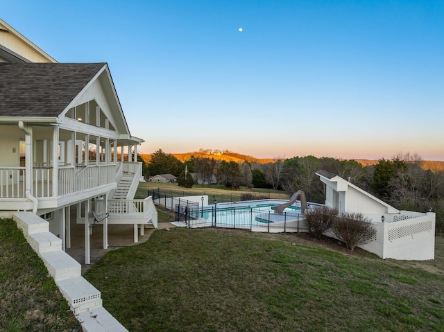 yard at dusk featuring a patio, stairway, fence, and a fenced in pool