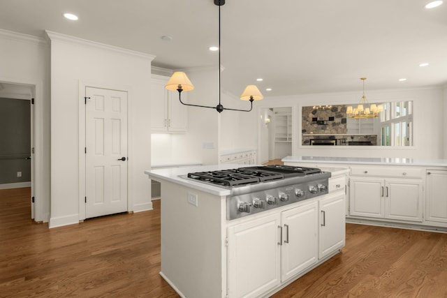 kitchen with stainless steel gas stovetop, a center island, crown molding, and light countertops