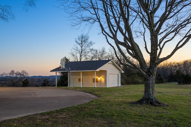 view of front of home with an outdoor structure, a front lawn, a detached garage, and a chimney