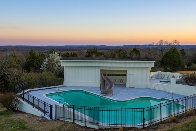 pool at dusk with a patio, fence, a fenced in pool, and a water slide