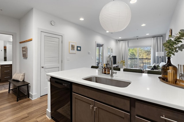 kitchen featuring dark brown cabinetry, dishwasher, light wood-style floors, and a sink