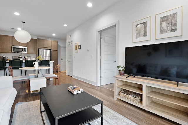 living room featuring recessed lighting, baseboards, and light wood-style floors