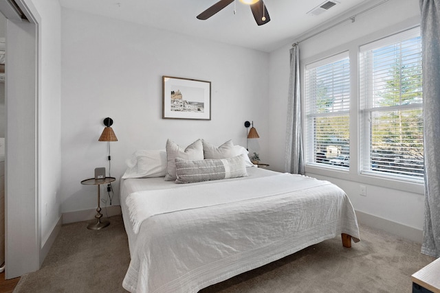 carpeted bedroom with visible vents, a ceiling fan, and baseboards