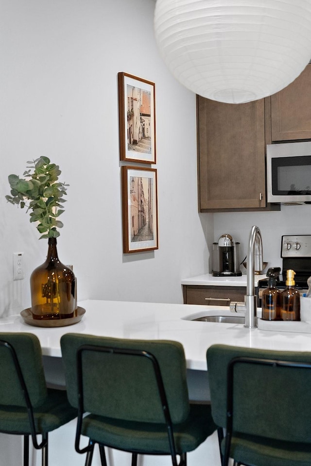 kitchen with a sink, stainless steel appliances, dark brown cabinets, and light countertops