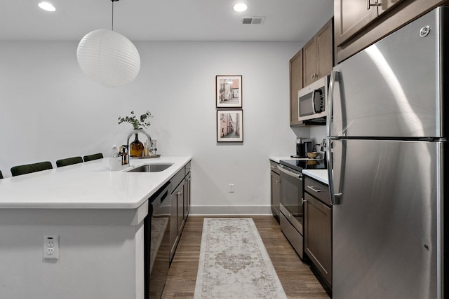 kitchen featuring visible vents, light countertops, appliances with stainless steel finishes, a peninsula, and a sink