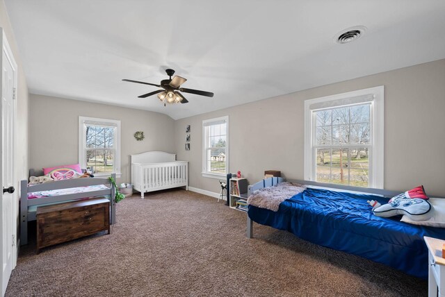 carpeted bedroom with visible vents, multiple windows, baseboards, and a ceiling fan