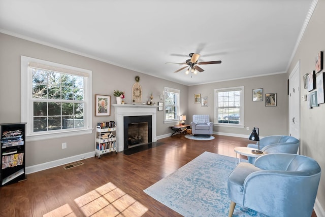 living area featuring visible vents, ornamental molding, a fireplace with flush hearth, and wood finished floors