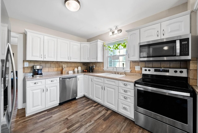 kitchen featuring light countertops, decorative backsplash, dark wood-style floors, stainless steel appliances, and a sink