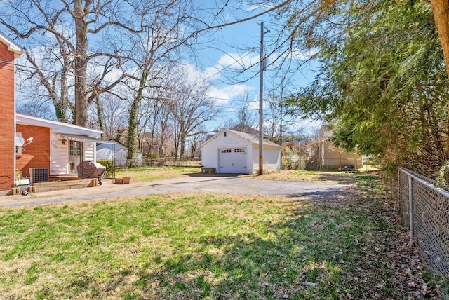 view of yard with driveway, a detached garage, an outdoor structure, and fence