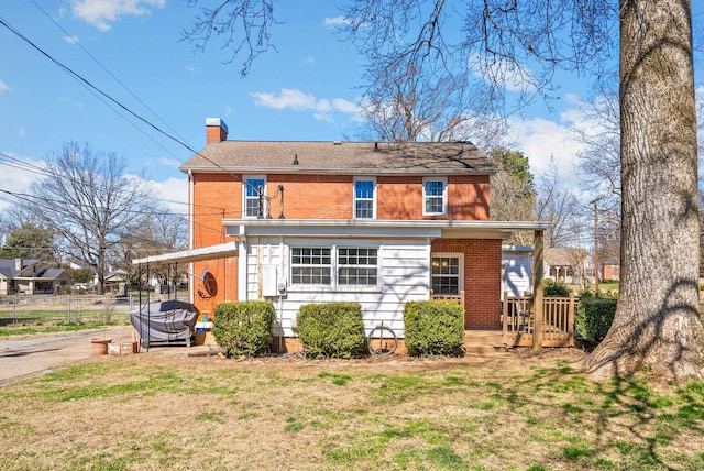 back of house featuring brick siding, a chimney, a yard, and fence