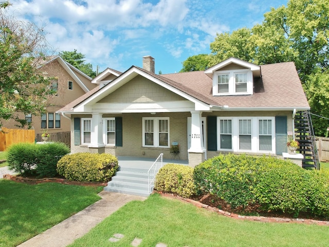 view of front of property with brick siding, fence, stairway, a porch, and a chimney