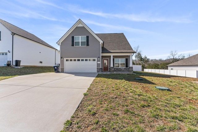 traditional-style house with stone siding, fence, concrete driveway, a front yard, and an attached garage