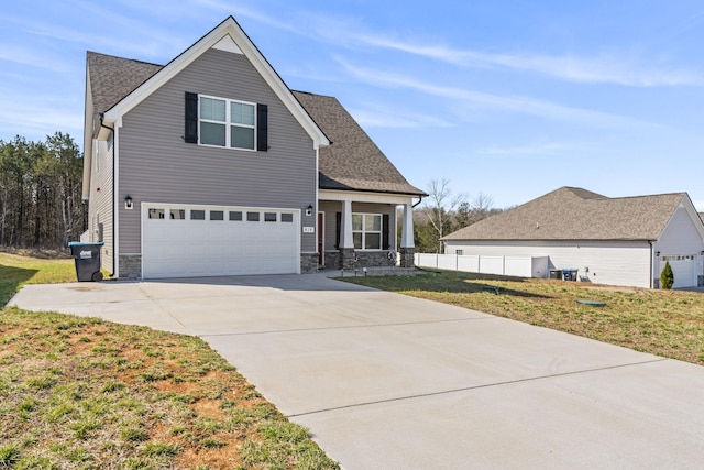 view of front of house with driveway, a front lawn, stone siding, an attached garage, and a shingled roof