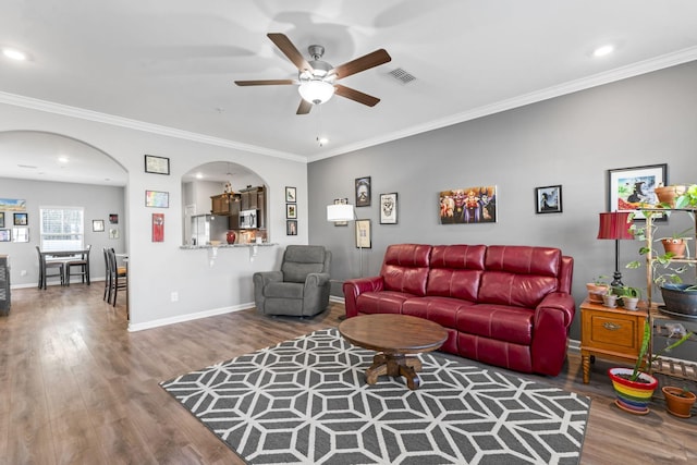 living room with arched walkways, visible vents, crown molding, and wood finished floors