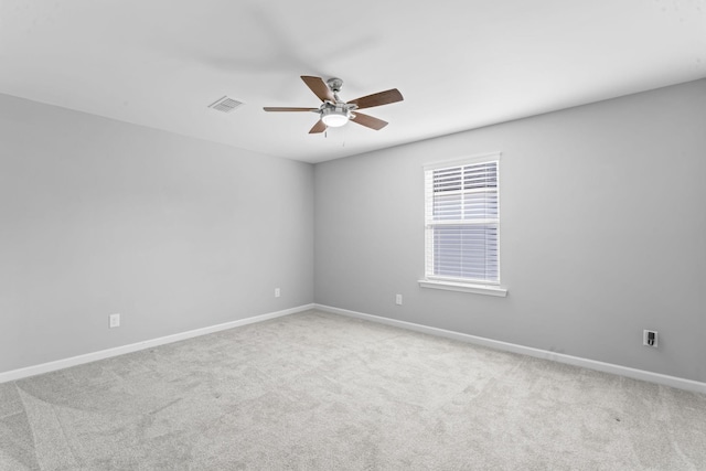 carpeted spare room featuring visible vents, baseboards, and ceiling fan