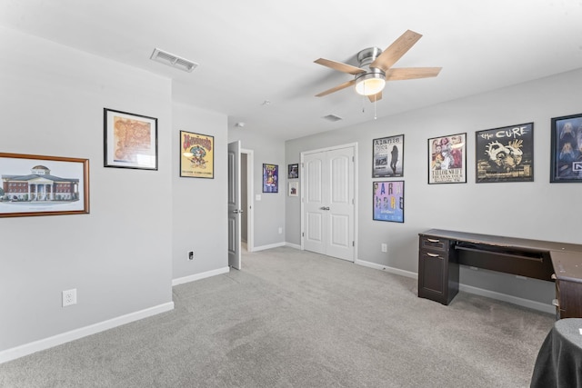 unfurnished office featuring visible vents, light colored carpet, a ceiling fan, and baseboards