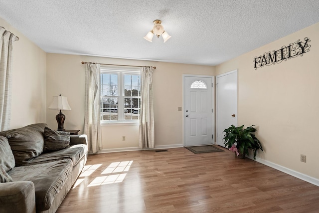 entryway with light wood-style flooring, baseboards, visible vents, and a textured ceiling