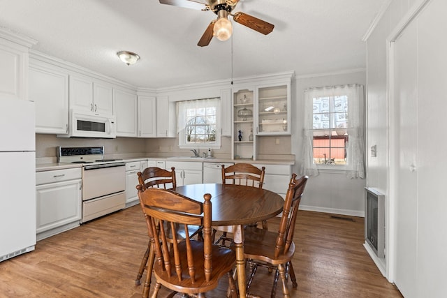 dining space with a ceiling fan, baseboards, wood finished floors, visible vents, and ornamental molding