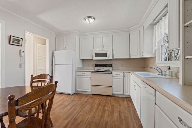 kitchen with light wood-type flooring, a sink, white appliances, white cabinets, and light countertops