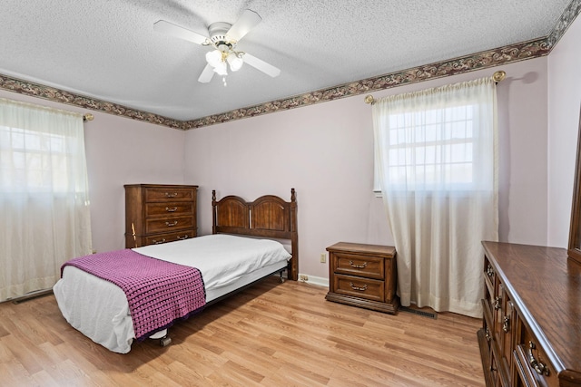 bedroom featuring ceiling fan, light wood-style floors, and a textured ceiling