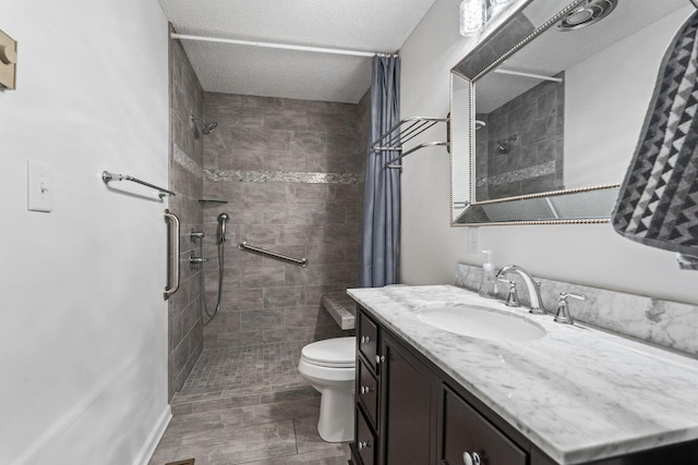 full bath featuring vanity, toilet, a tile shower, and a textured ceiling