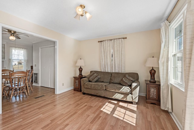 living area with visible vents, ceiling fan, baseboards, and light wood-style floors