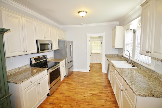 kitchen with a sink, ornamental molding, light wood-type flooring, and stainless steel appliances