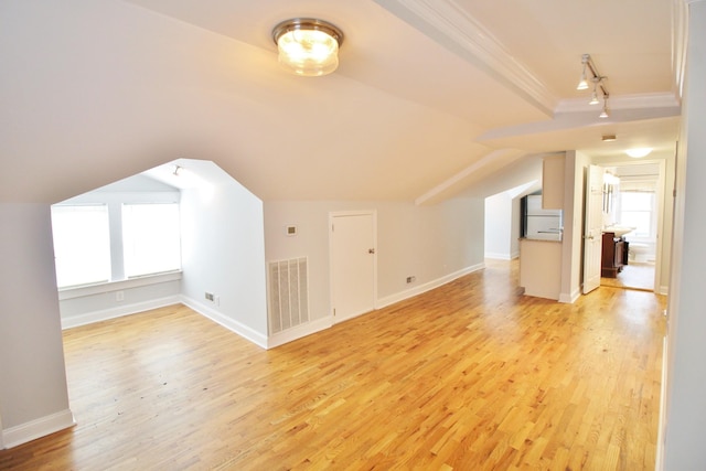 additional living space with visible vents, lofted ceiling, light wood-type flooring, and baseboards