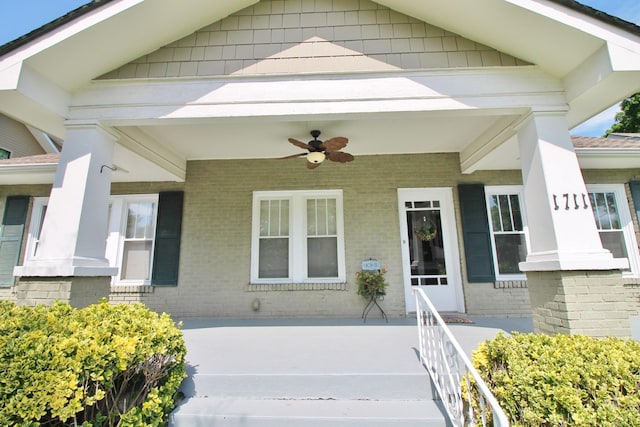 entrance to property featuring covered porch, brick siding, and ceiling fan