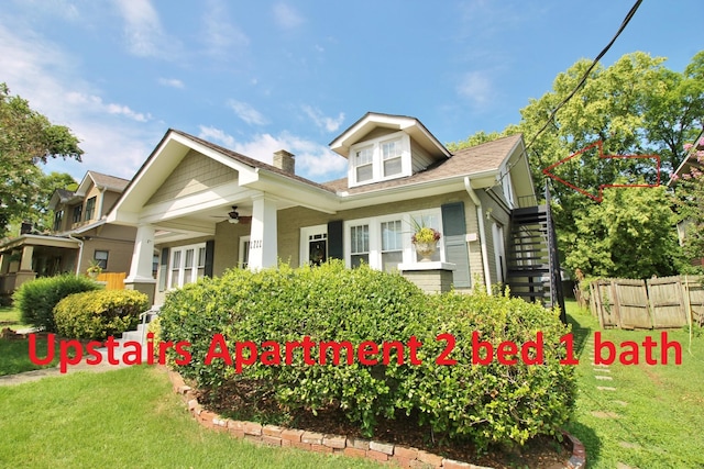 view of front facade featuring ceiling fan, stairs, a front lawn, and fence