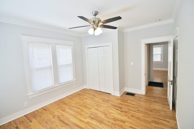 unfurnished bedroom featuring light wood-type flooring, visible vents, baseboards, and crown molding