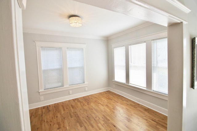 spare room featuring baseboards, light wood-style floors, and ornamental molding